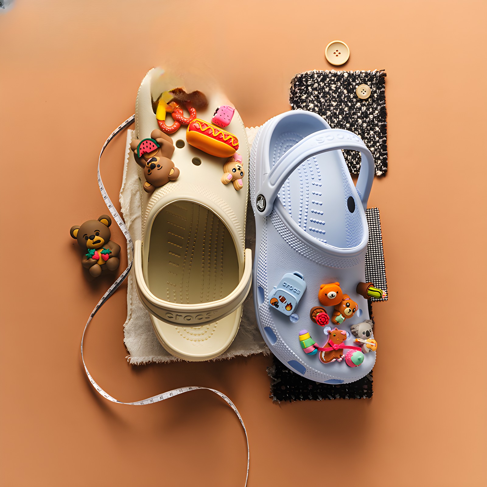 Top-down view of two CROCS clogs, one beige and one light blue, adorned with playful food and animal-themed Jibbitz charms on an orange background